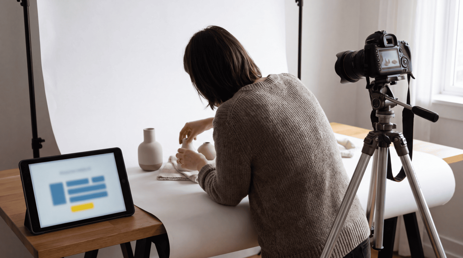 Web developer reviewing website analytics on laptop while recording video content with professional camera